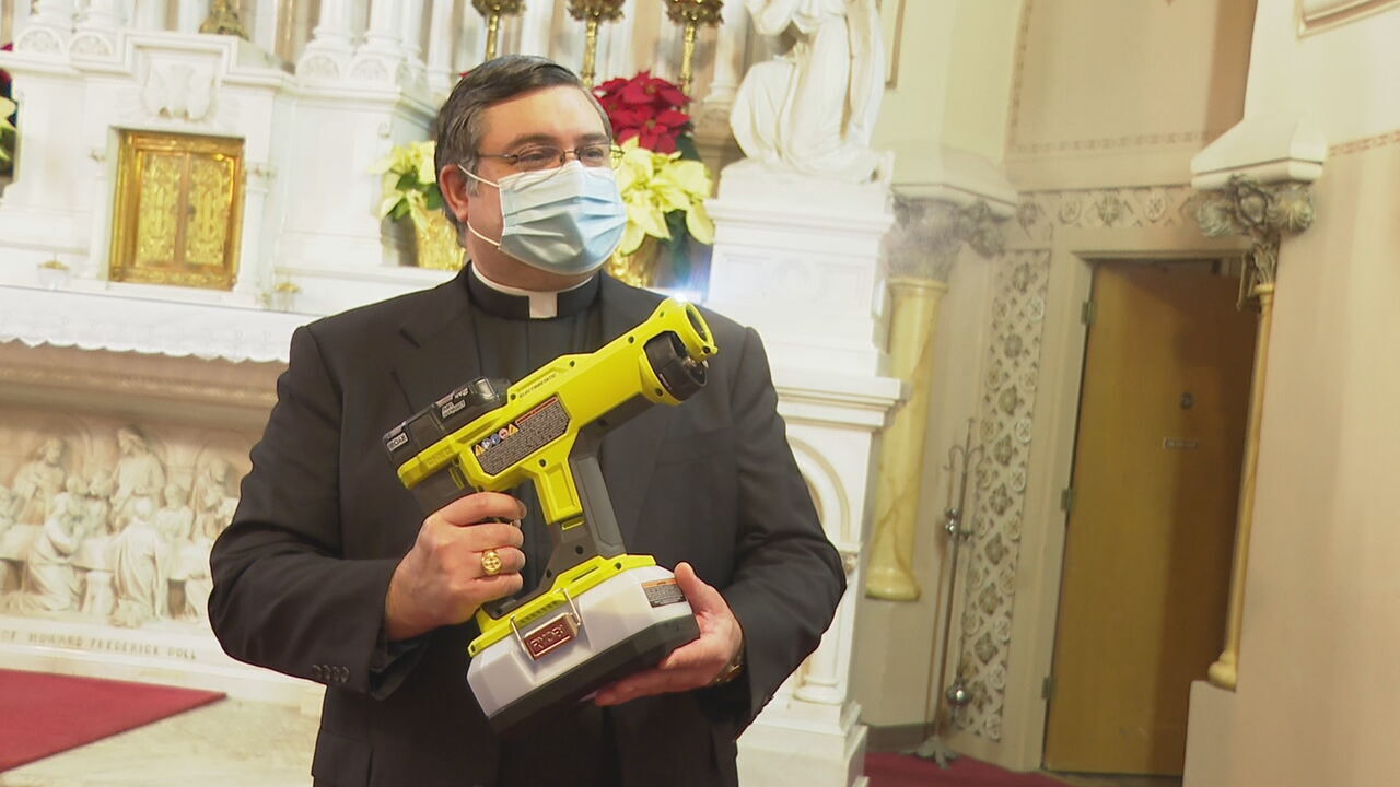 Father Duane Trombetta with sanitizing spray gun